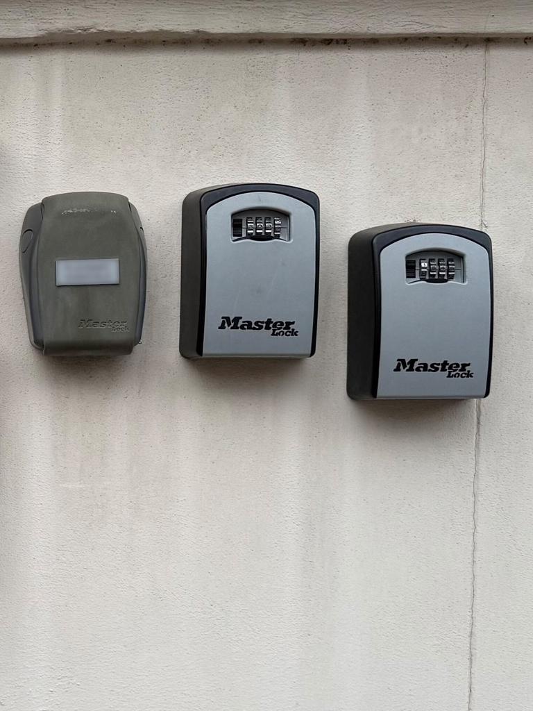 An einer Hauswand hängen neben einen Briefkasten mehrere Schlüsselkästen für Wohnungen, die über Internetplattformen wie Airbnb vermietet werden. Die 