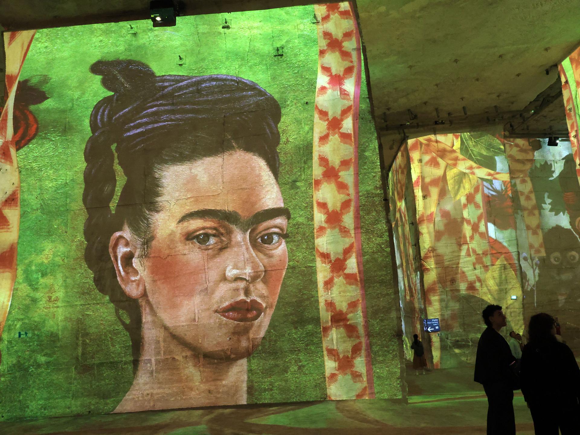 In einem dunklen Raum sind Gemälde an die Wand projeziert. Darunter ist auch ein Selbstporträt der mexikanischen Künstlerin Frida Kahlo. 