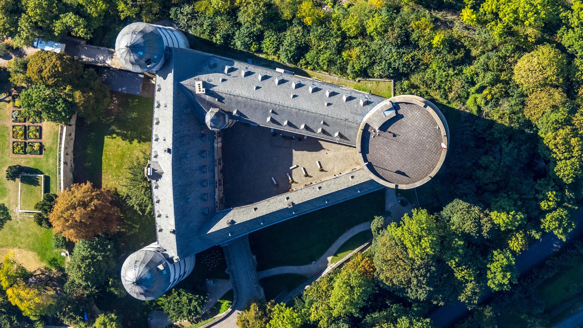 Luftbild einer Burg: Es ist die Wewelsburg bei Paderborn. Es ist ein dreiseitiges Bauwerk mit Türmen an jeder Ecke. 