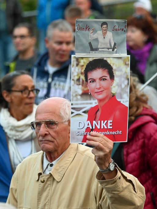 Ein Teilnehmer einer Demonstration in Halle hält ein Foto von Sahra Wagenknecht und den Worten "Danke Sahra Wagenknecht" hoch. "