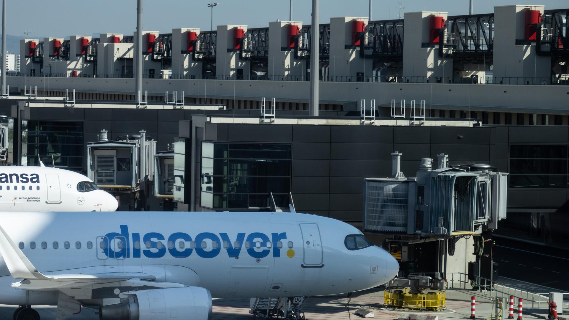 Flugzeuge verschiedener Airlines, darunter Discover, stehen an den Fingern des neuen Terminals. 