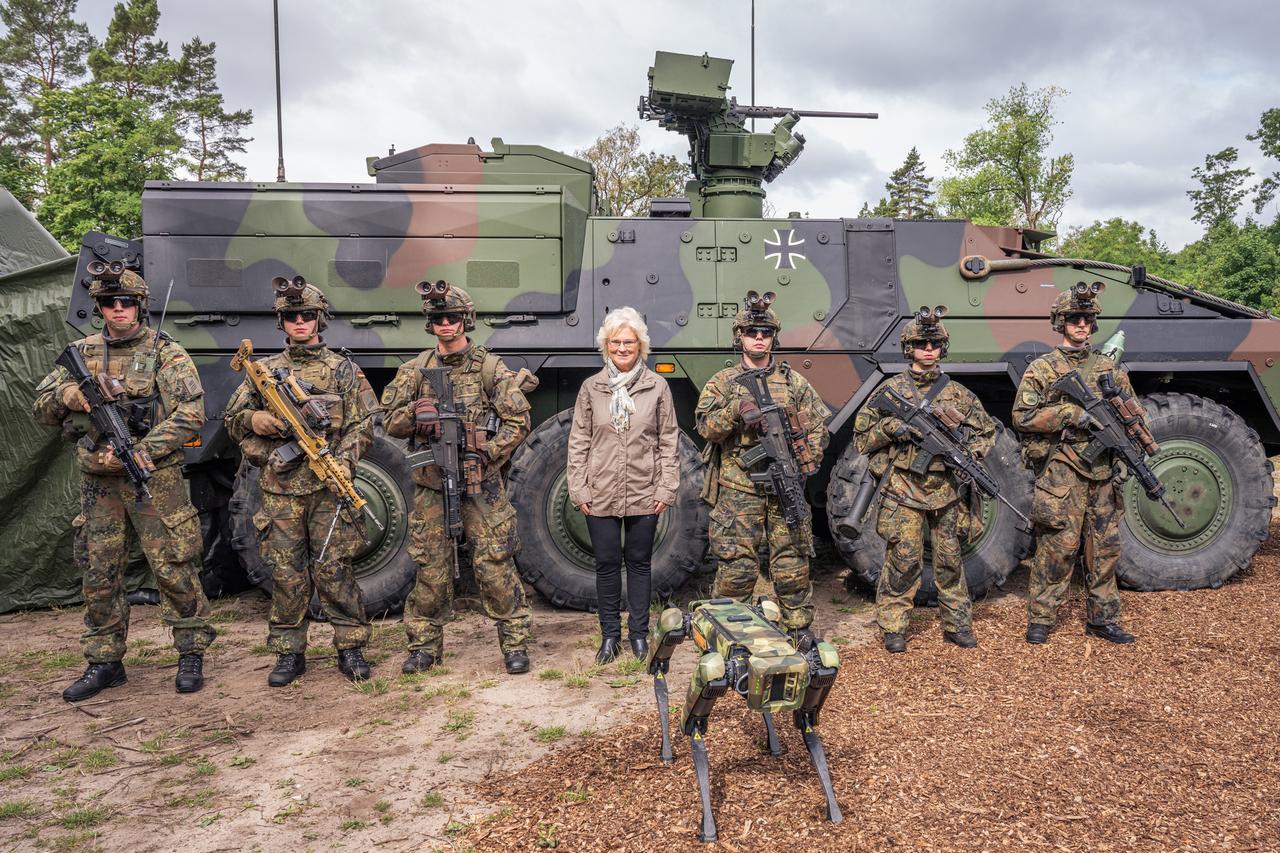 Bundesverteidigungsministerin Christine Lambrecht posiert mit sechs Soldaten und einem Roboterhund vor einem Boxer-Panzer