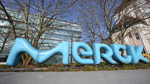 Ein Marken-Logo der Merck KGaA steht vor dem Unternehmensgelände. 