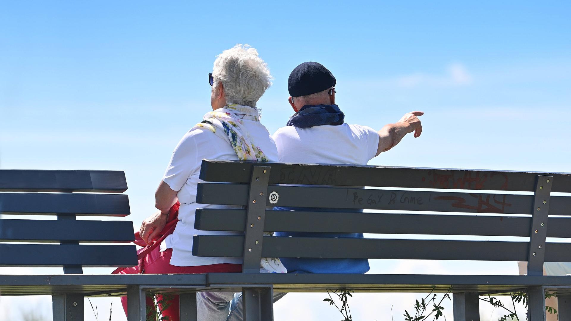 Älteres Ehepaar-Rentner - Mann und Frau -  sitzen auf einer Bank im Freien.