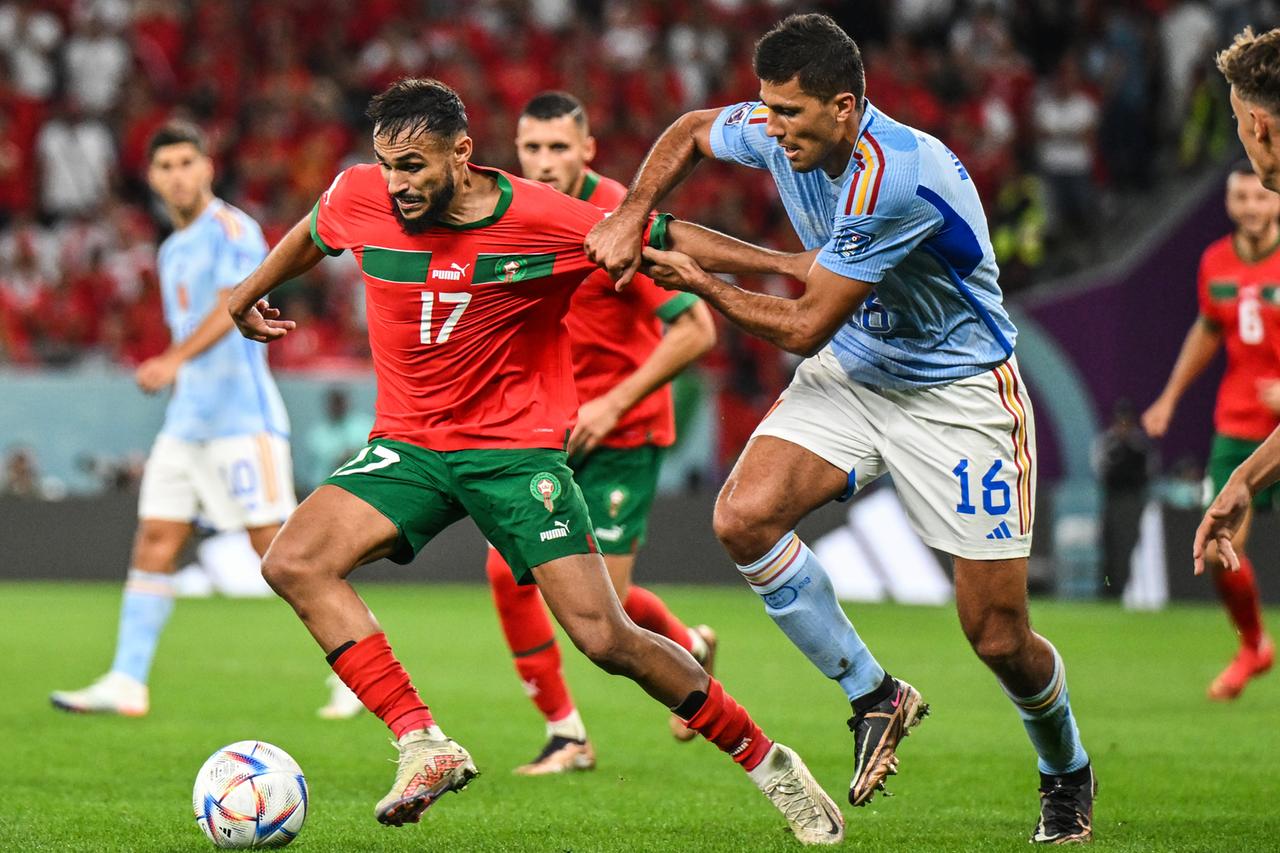 Das Bild zeigt die Fußballspieler Boufal (Marokko) und Rodri (Spanien) im Zweikampf. 