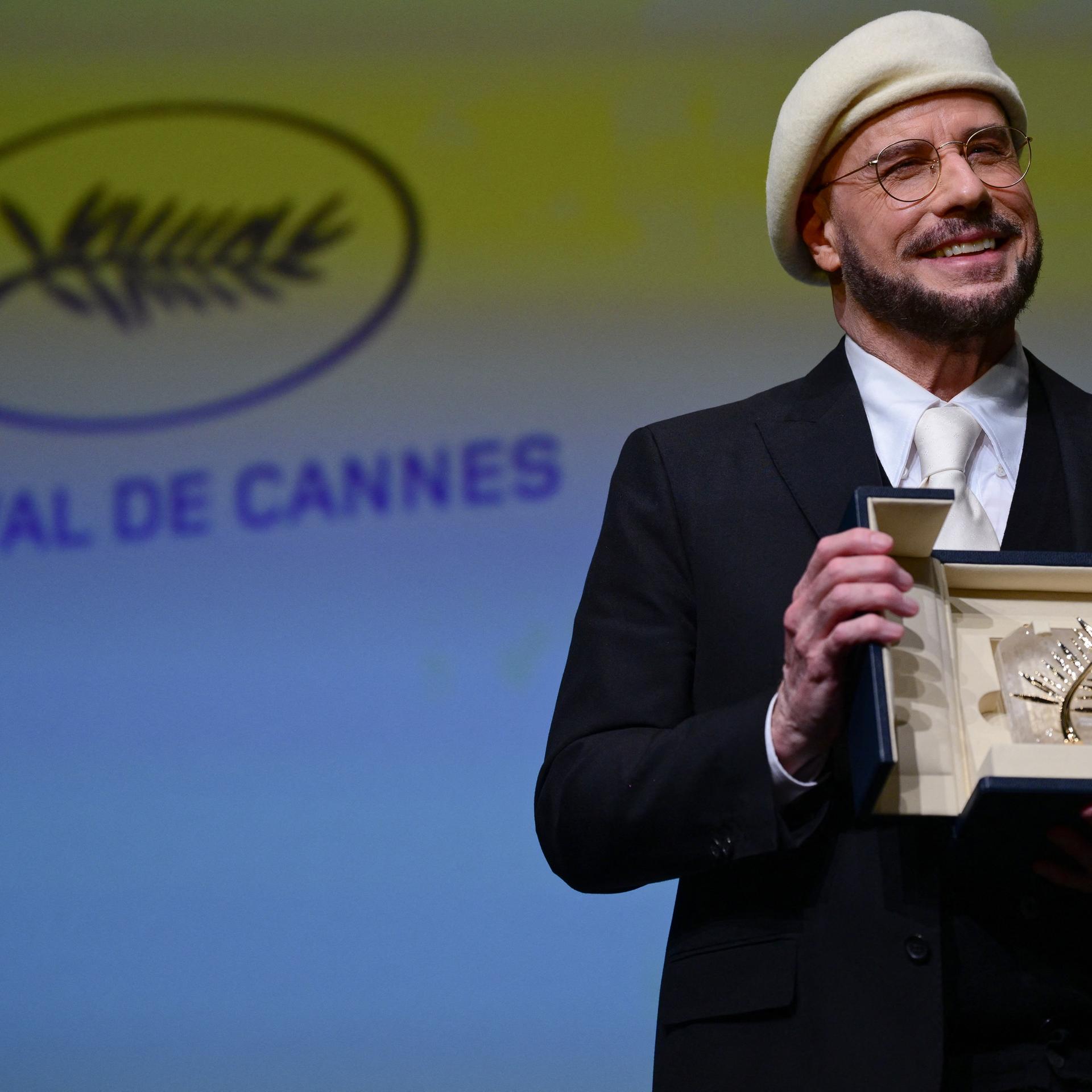 Das Foto zeigt den US-Schauspieler und Regisseur, John Travolta, mit der Ehrenpalme in Cannes. 
