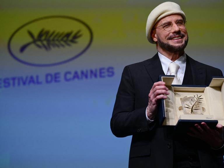 Das Foto zeigt den US-Schauspieler und Regisseur, John Travolta, mit der Ehrenpalme in Cannes.
      