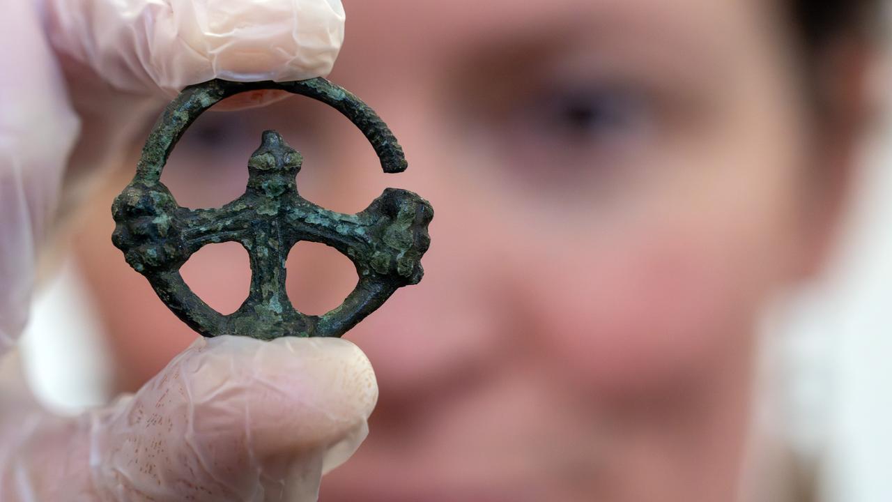 Juliane Rangnow, ehrenamtliche Bodendenkmalpflegerin, hält vor Beginn einer Pressekonferenz das von ihr gefundene Radkreuz aus dem 10. Jahrhundert in der Hand.