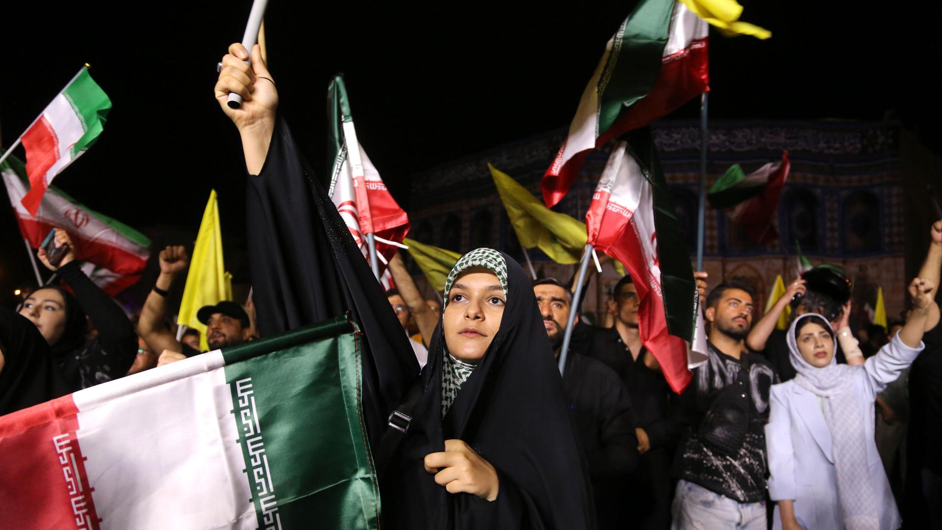 Demonstrantinnen und Demonstranten schwenken iranische, palästinensische und Hisbollah-Flaggen.