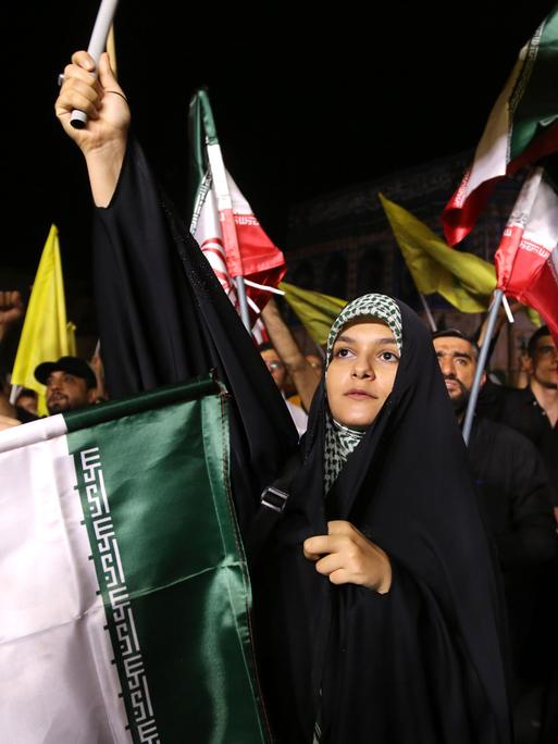 Demonstrantinnen und Demonstranten schwenken iranische, palästinensische und Hisbollah-Flaggen.