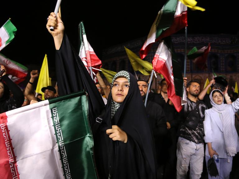 Demonstrantinnen und Demonstranten schwenken iranische, palästinensische und Hisbollah-Flaggen.