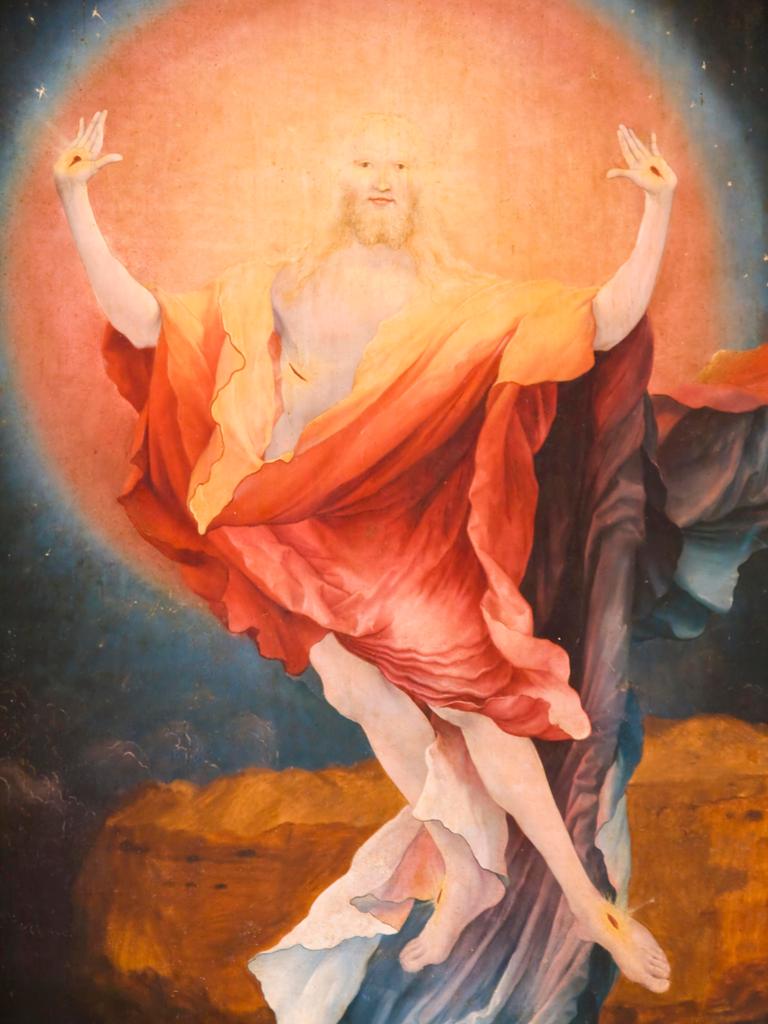 "Die Auferstehung Christi", Detail aus dem Altarbild von Matthias Grünewald in Colmar in Frankreich. Jesus streckt seine Arme aus vor hellem orangefarbenem Licht.