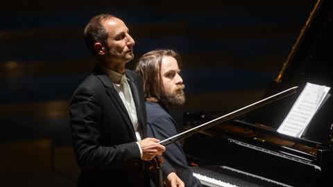 Ein Geiger steht mit geschlossenen Augen vor einem Pianisten.