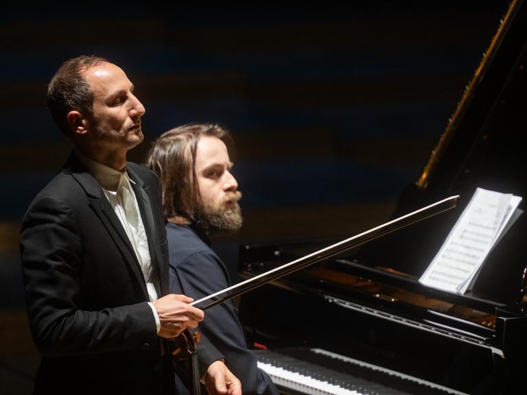 Ein Geiger steht mit geschlossenen Augen vor einem Pianisten.