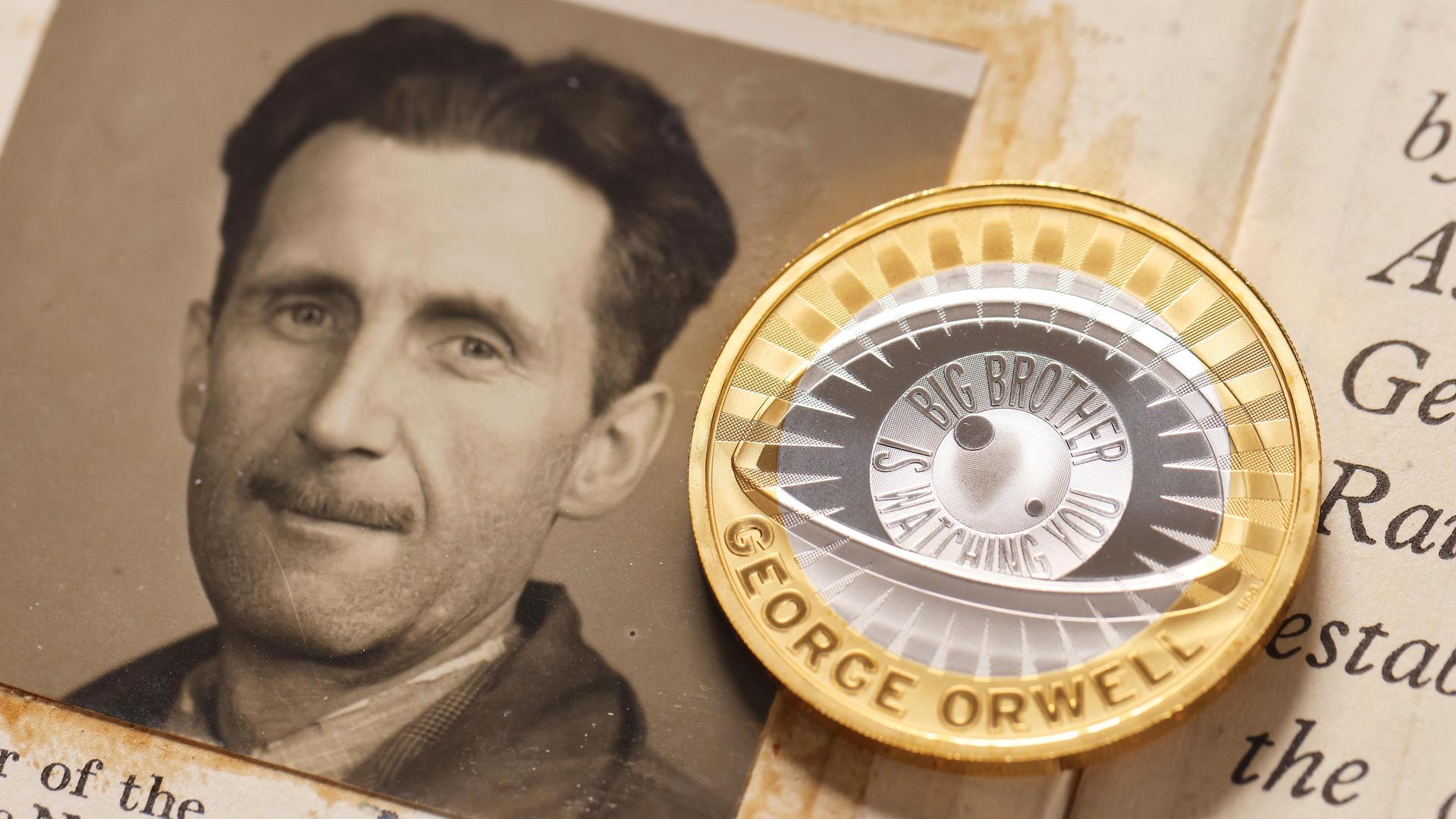 Passfoto von George Orwell neben einer neuen 2-Pfund-Münze, die in Großbritannien zu Ehren des Schriftstellers geprägt wurde