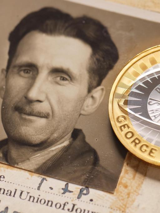 Passfoto von George Orwell neben einer neuen 2-Pfund-Münze, die in Großbritannien zu Ehren des Schriftstellers geprägt wurde