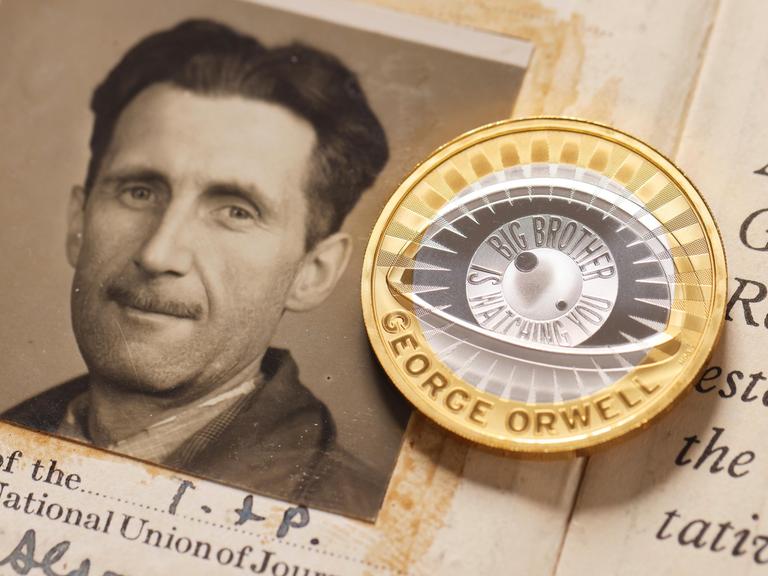 Passfoto von George Orwell neben einer neuen 2-Pfund-Münze, die in Großbritannien zu Ehren des Schriftstellers geprägt wurde
