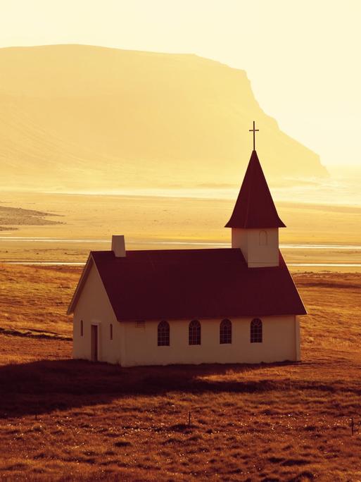 Eine abgeschiedene Kirche am Strand bei Sonnenuntergang.