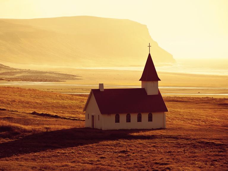 Eine abgeschiedene Kirche am Strand bei Sonnenuntergang.