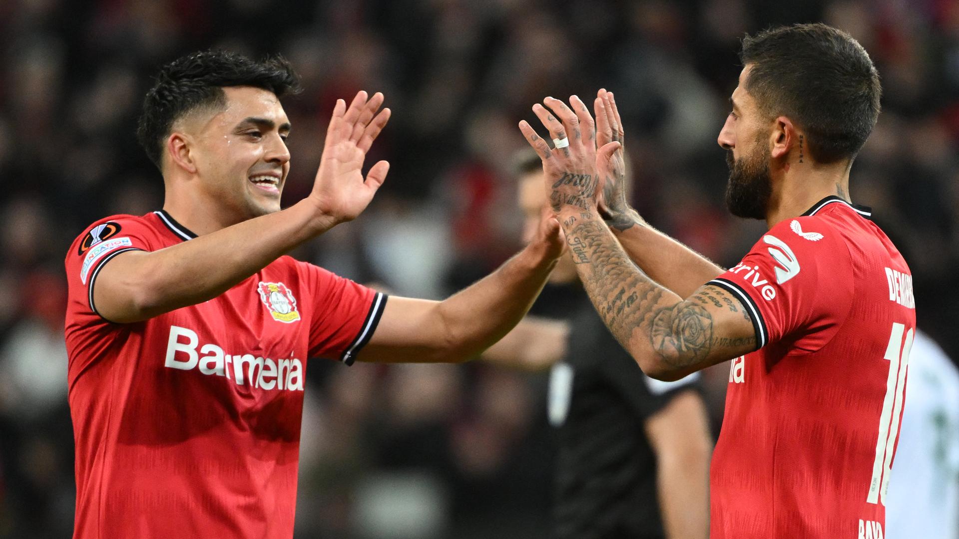 Zwei Fußballspieler in roten Trikots klatschen sich ab.