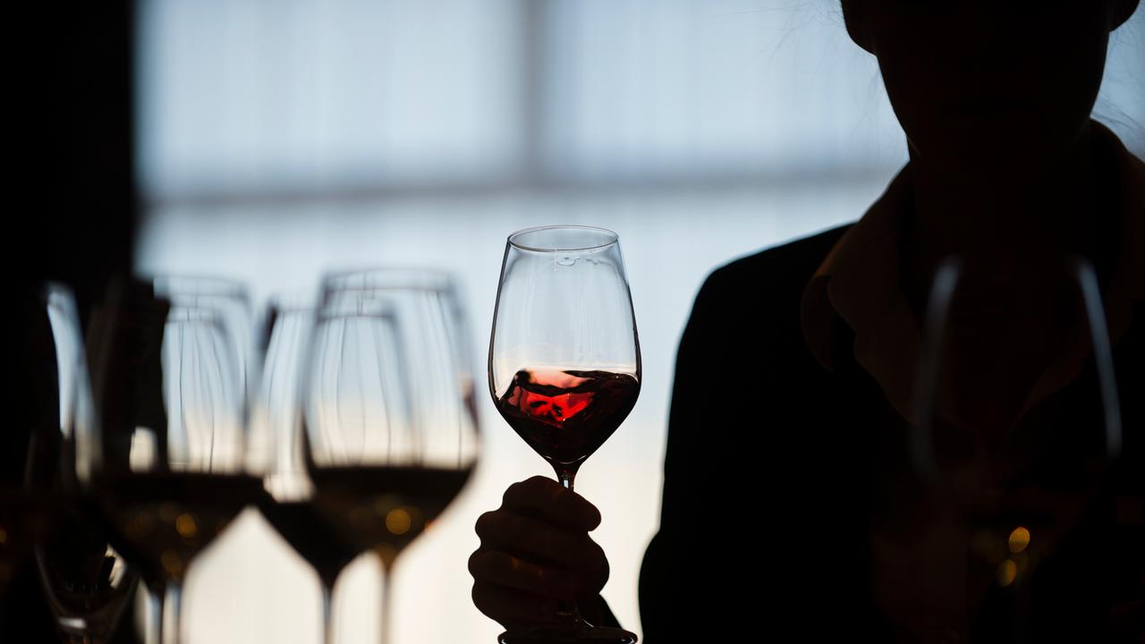 Eine Teilnehmerin schwenkt während einer Weinverkostung einen Rotwein im Glas.