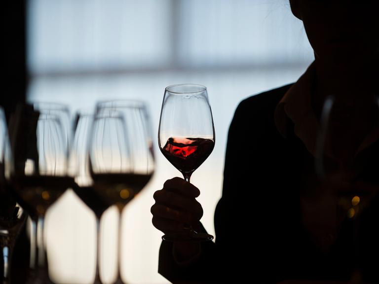 Eine Teilnehmerin schwenkt während einer Weinverkostung einen Rotwein im Glas. Foto: Gregor Fischer/dpa ++