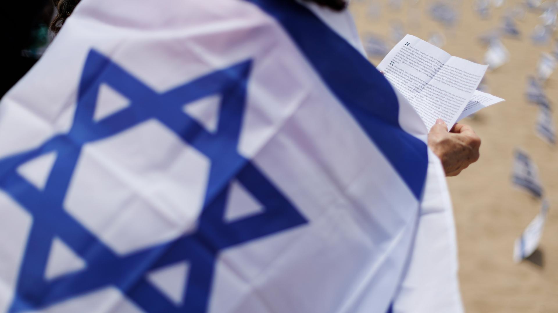 Ein Mensch betet in eine Israel-Fahne gehüllt.