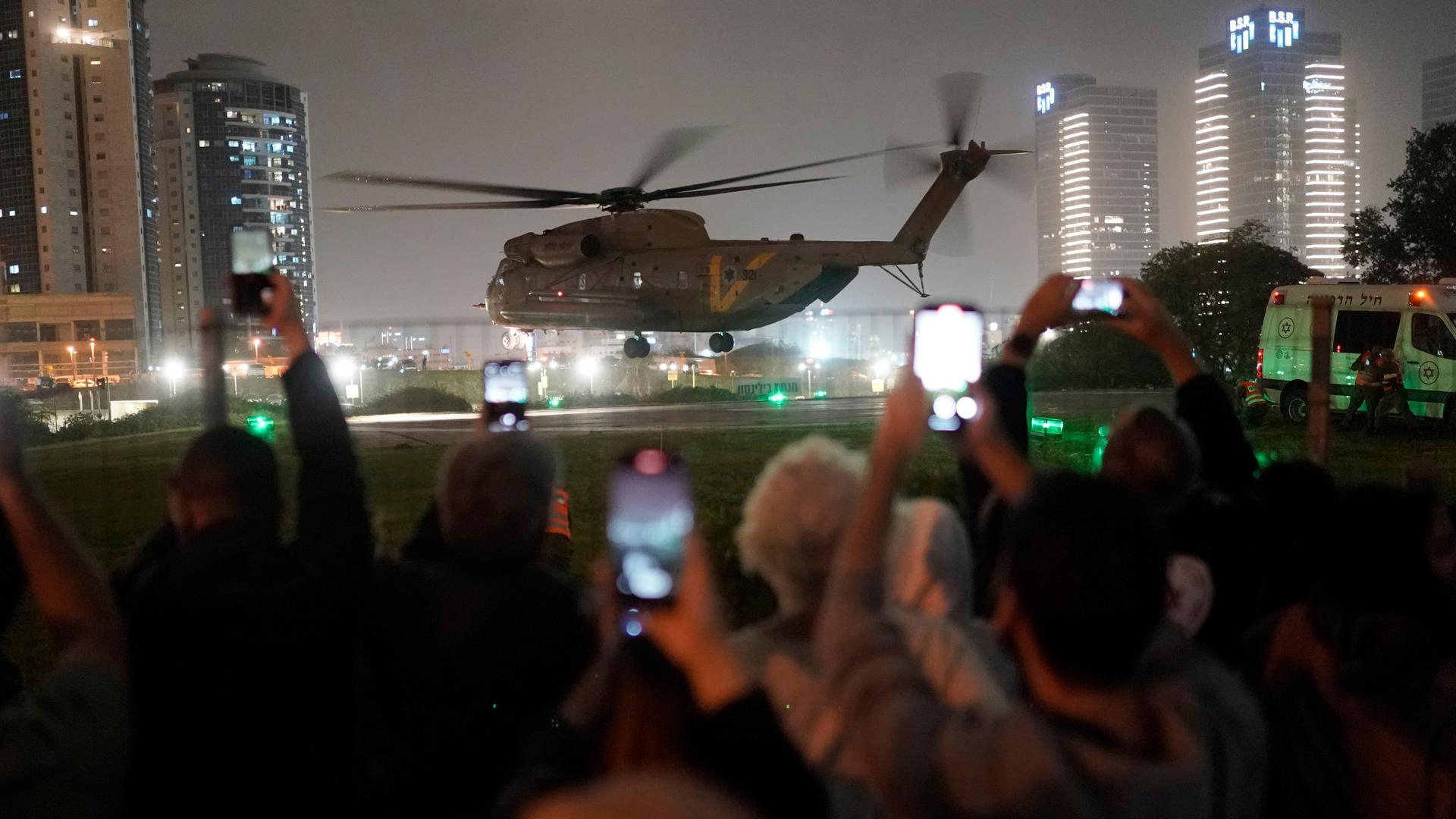 Menschen jubeln und filmen, während ein Helikopter mit den freigelassenen Geiseln landet.