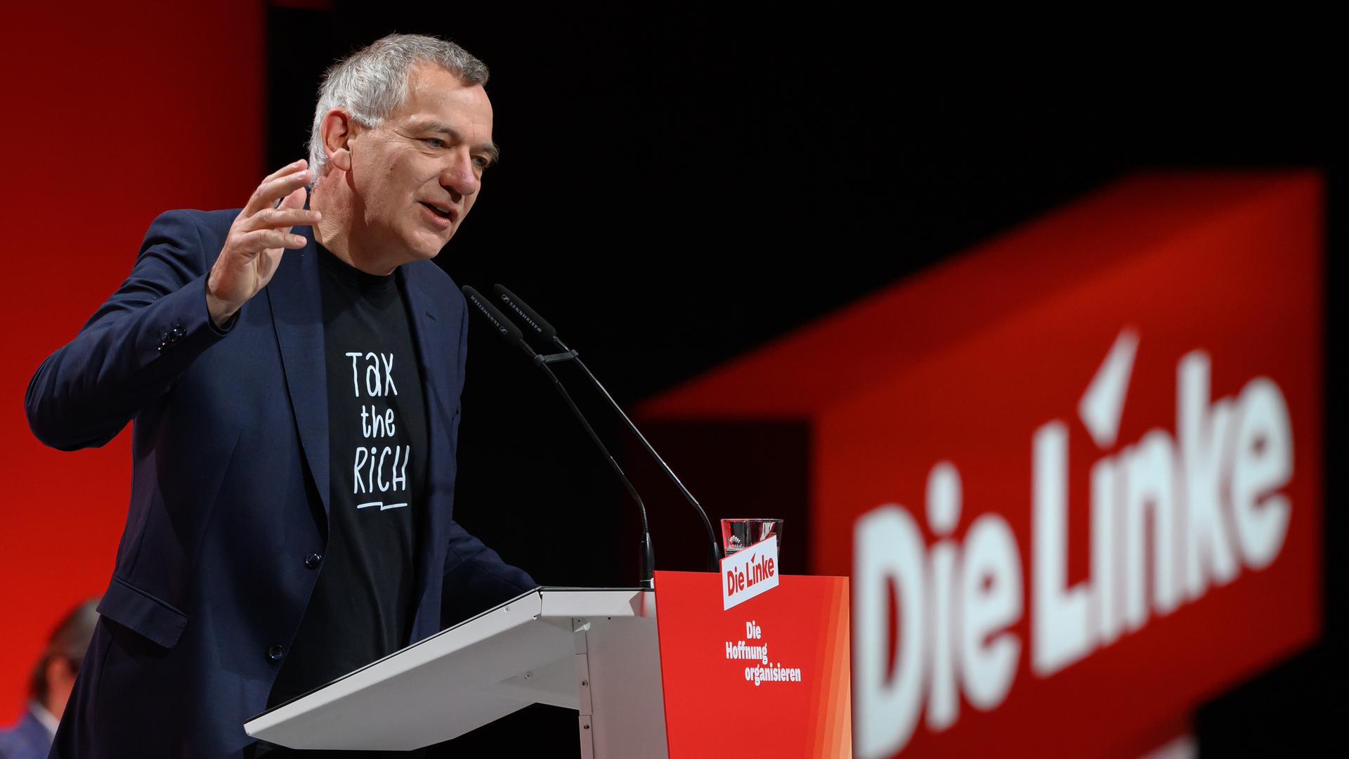 Jan van Aken steht am Rednerpult und gestikuliert mit der rechten Hand. Jan van Aken steht am Rednerpult und gestikuliert mit der rechten Hand.