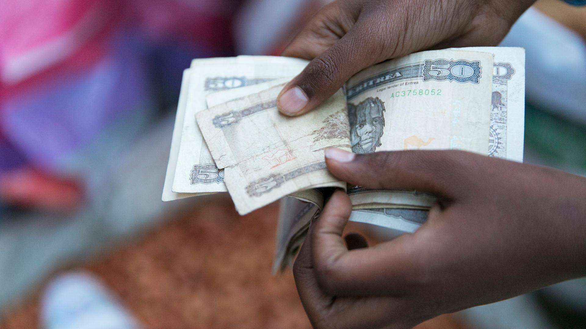 Marktszene in der Altstadt von Asmara in Eritrea: Hände zählen Geldscheine aus einem Bündel heraus. Marktszene in der Altstadt von Asmara in Eritrea: Hände zählen Geldscheine aus einem Bündel heraus.