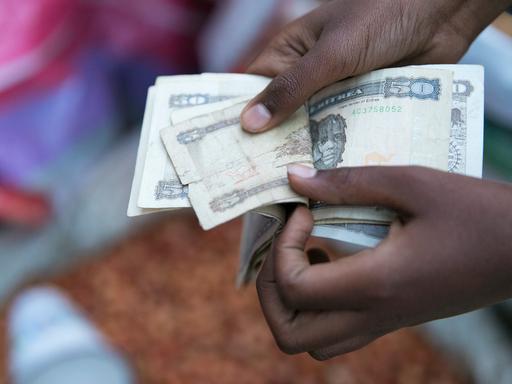 Marktszene in der Altstadt von Asmara in Eritrea: Hände zählen Geldscheine aus einem Bündel heraus. Marktszene in der Altstadt von Asmara in Eritrea: Hände zählen Geldscheine aus einem Bündel heraus.