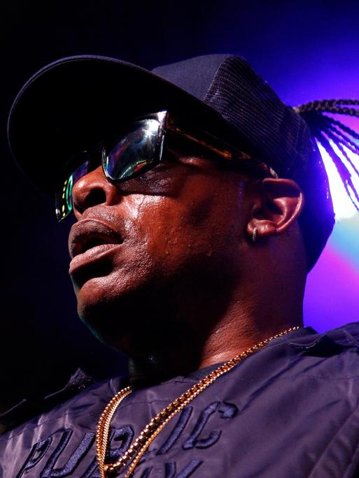 Porträt des Rappers Coolio 2019 in Las Vegas auf der Bühne. Er trägt eine dunkle Sonnenbrille und eine Baseball-Kappe.