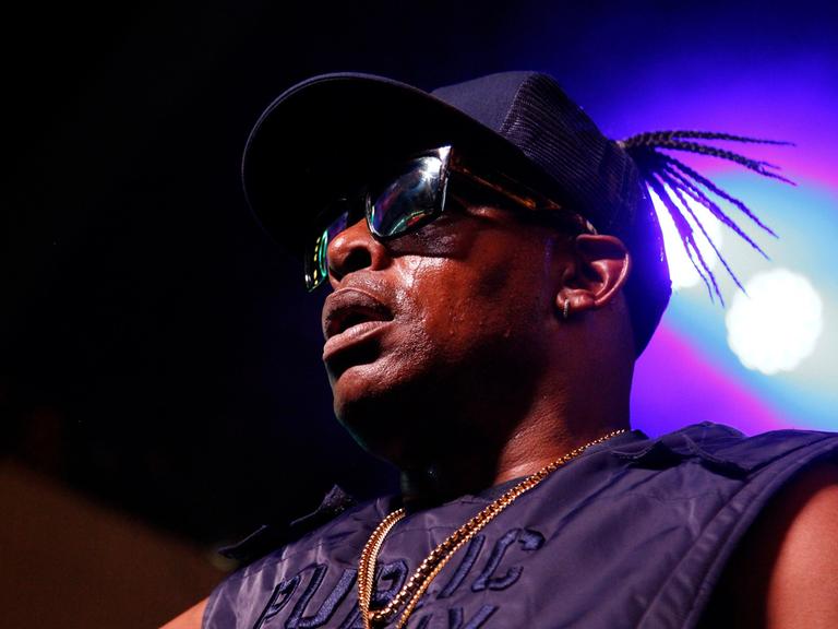 Porträt des Rappers Coolio 2019 in Las Vegas auf der Bühne. Er trägt eine dunkle Sonnenbrille und eine Baseball-Kappe.