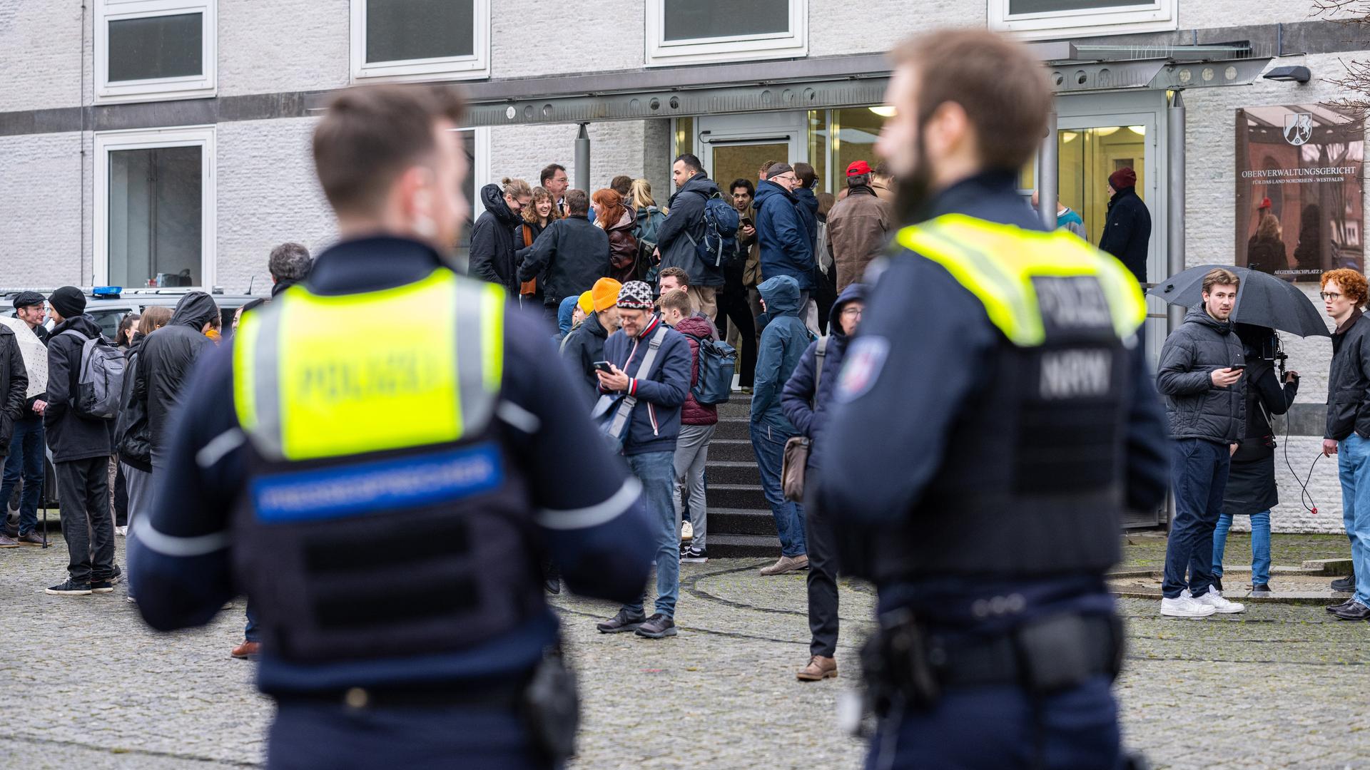 Polizisten und Teilnehmer der Verhandlung stehen vor dem Oberverwaltungsgericht in Münster.