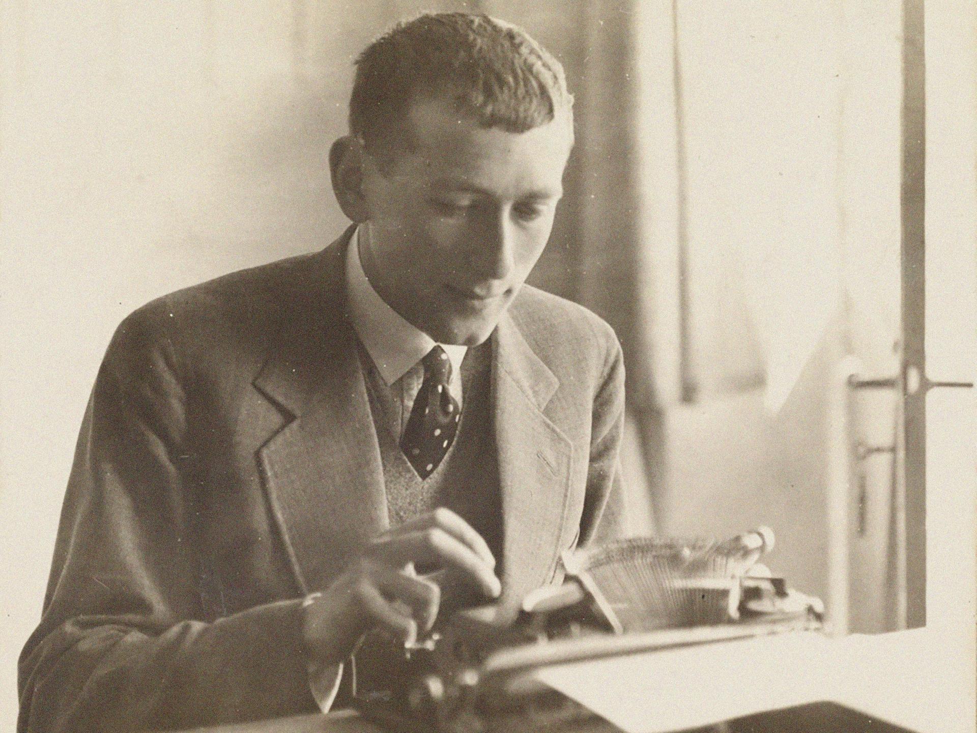 Der Architekt und Designer Marcel Breuer sitzt im Anzug mit Krawatte an einer Schreibmaschine und tippt. 