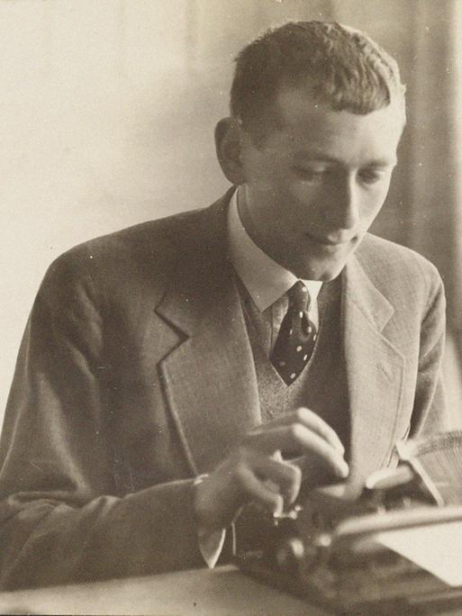 Der Architekt und Designer Marcel Breuer sitzt im Anzug mit Krawatte an einer Schreibmaschine und tippt. 