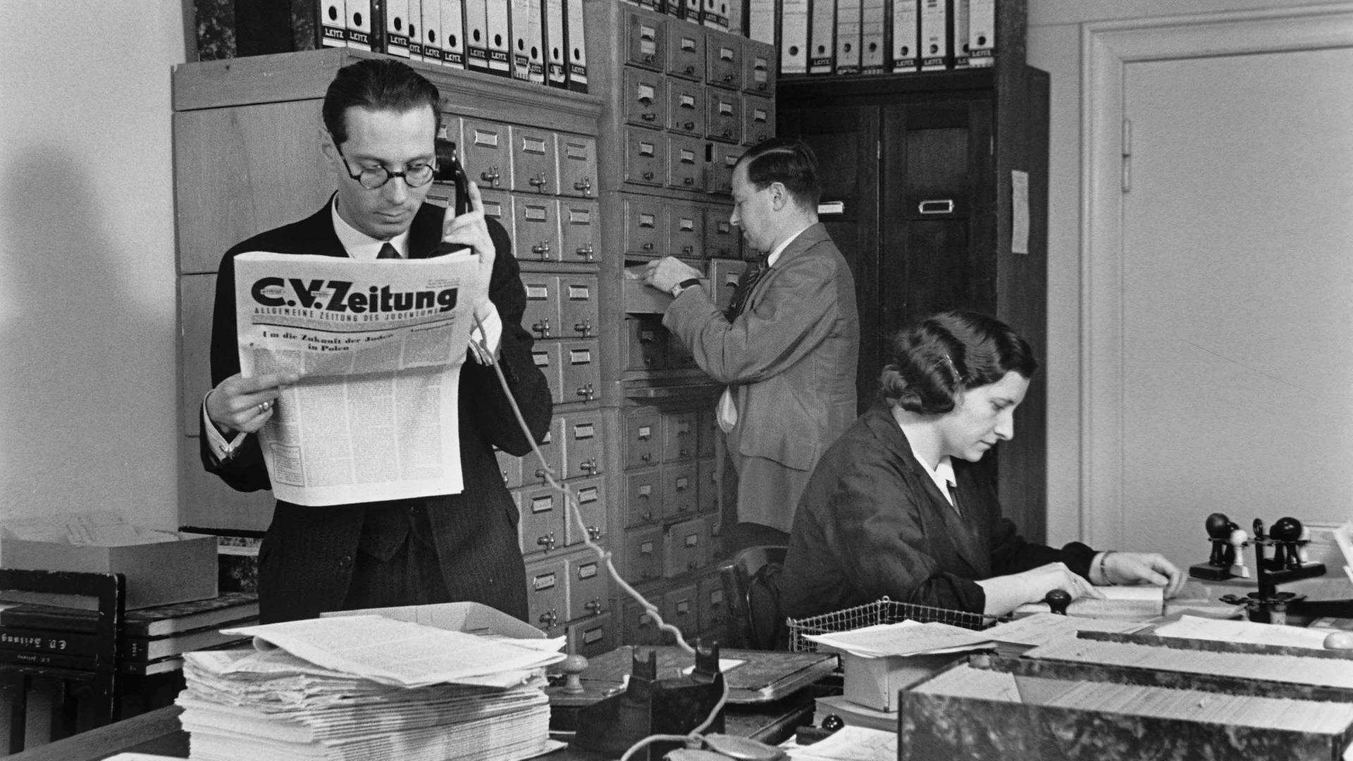 Hans Oppenheimer (im Vordergrund) mit zwei weiteren Mitarbeitenden in der Redaktion der C.V.-Zeitung