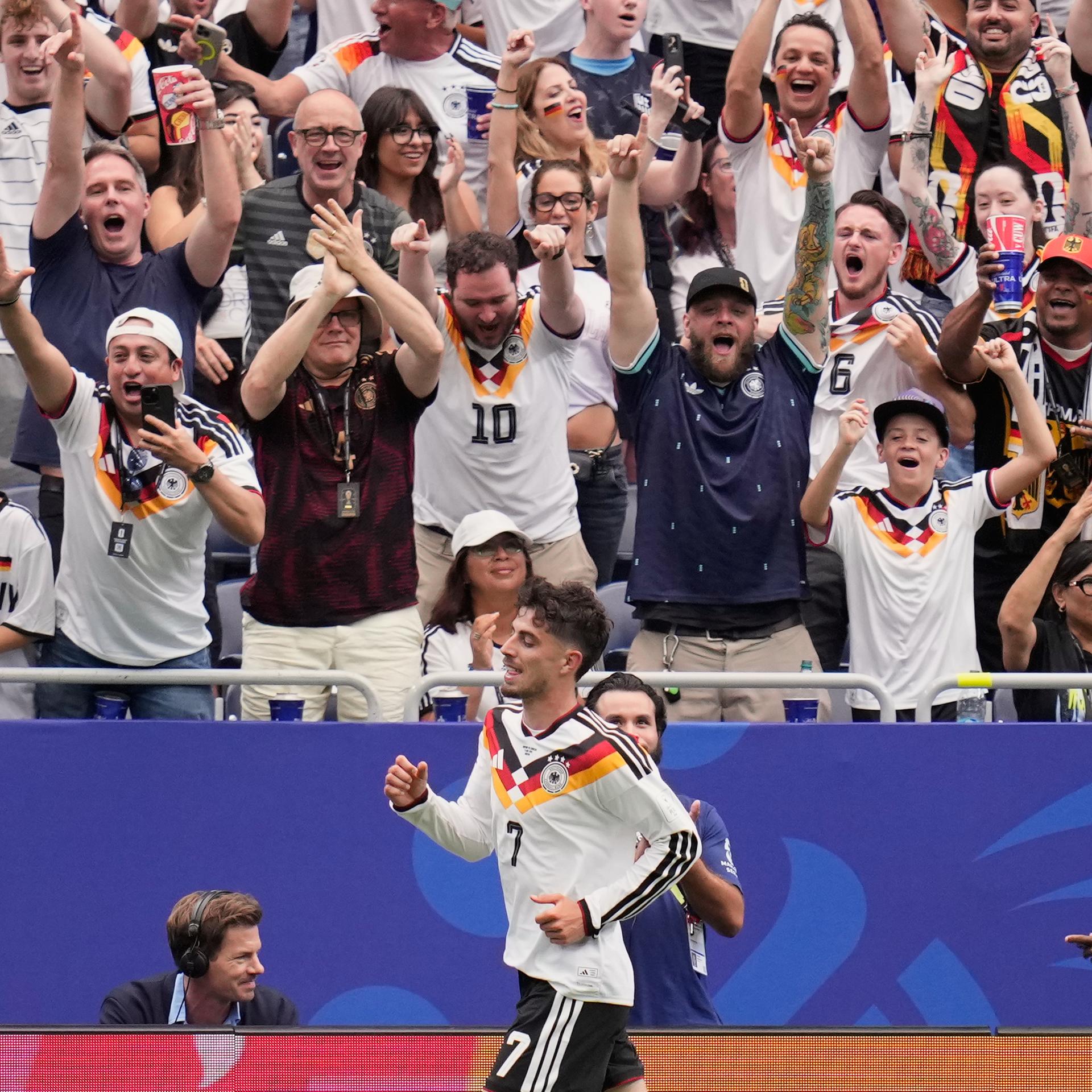 Kai Havertz läuft an der Tribüne mit feiernden Fans vorbei.