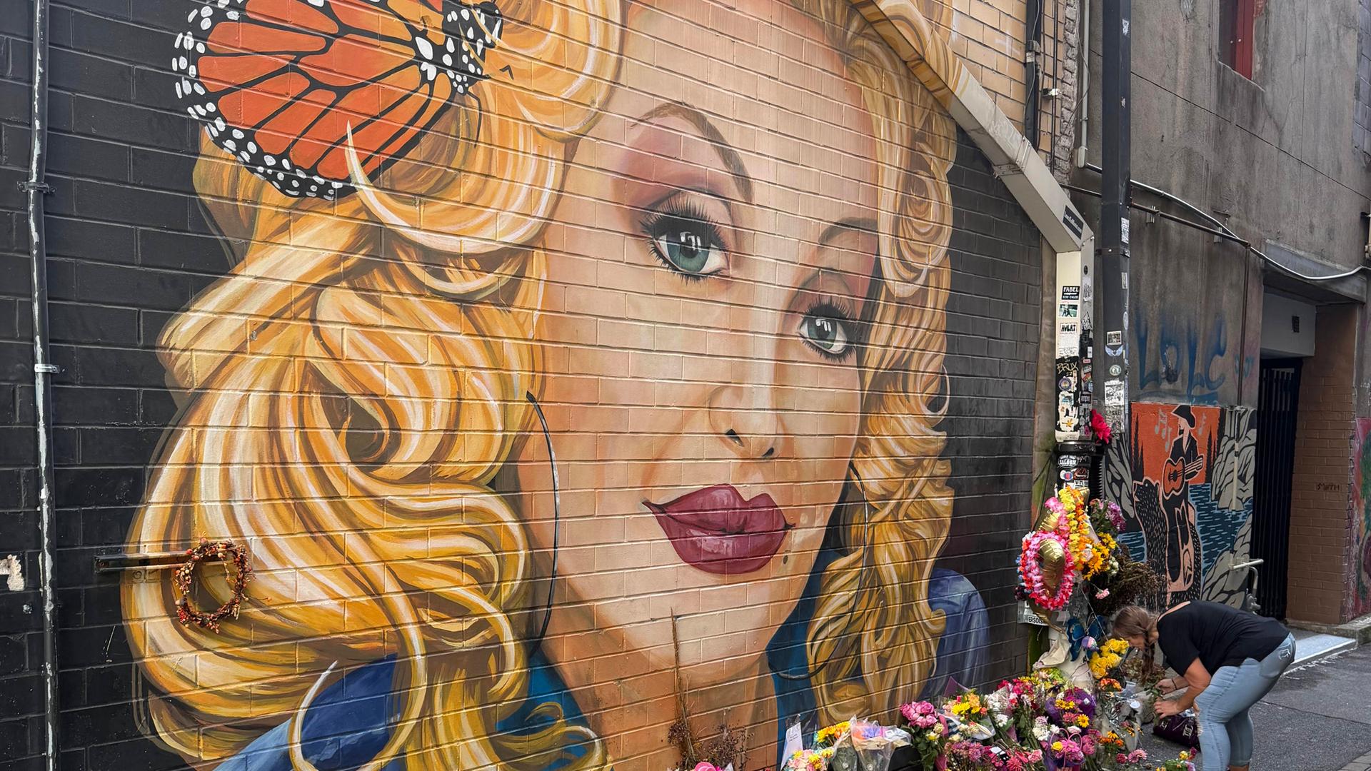 Eine Frau legt Blumen nieder an einem Graffiti von Dolly Parton in Knoxville, Tennessee Eine Frau legt Blumen nieder an einem Graffiti von Dolly Parton in Knoxville, Tennessee