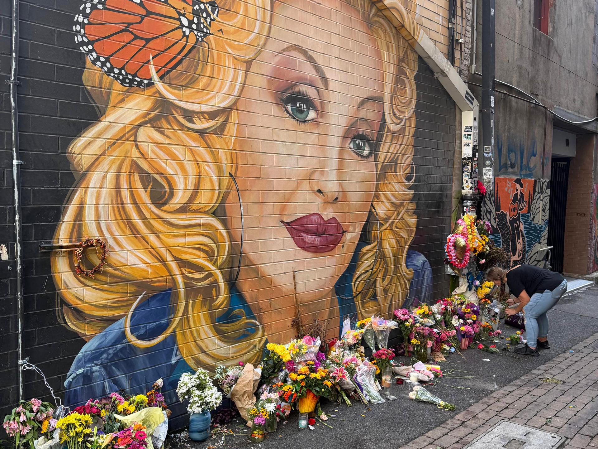 Eine Frau legt Blumen nieder an einem Graffiti von Dolly Parton in Knoxville, Tennessee Eine Frau legt Blumen nieder an einem Graffiti von Dolly Parton in Knoxville, Tennessee