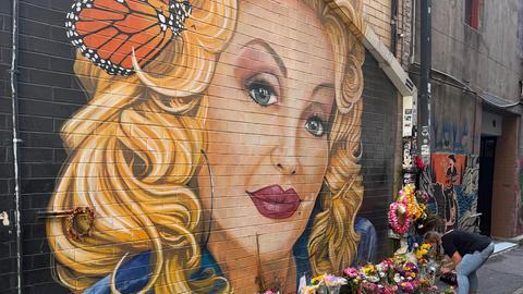 Eine Frau legt Blumen nieder an einem Graffiti von Dolly Parton in Knoxville, Tennessee Eine Frau legt Blumen nieder an einem Graffiti von Dolly Parton in Knoxville, Tennessee