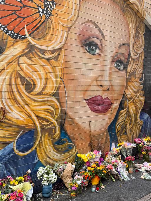 Eine Frau legt Blumen nieder an einem Graffiti von Dolly Parton in Knoxville, Tennessee 