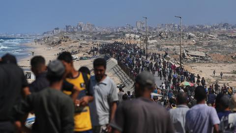 Bewohner des Gazastreifens gehen an der Küste entlang zu ihren Wohngebieten.