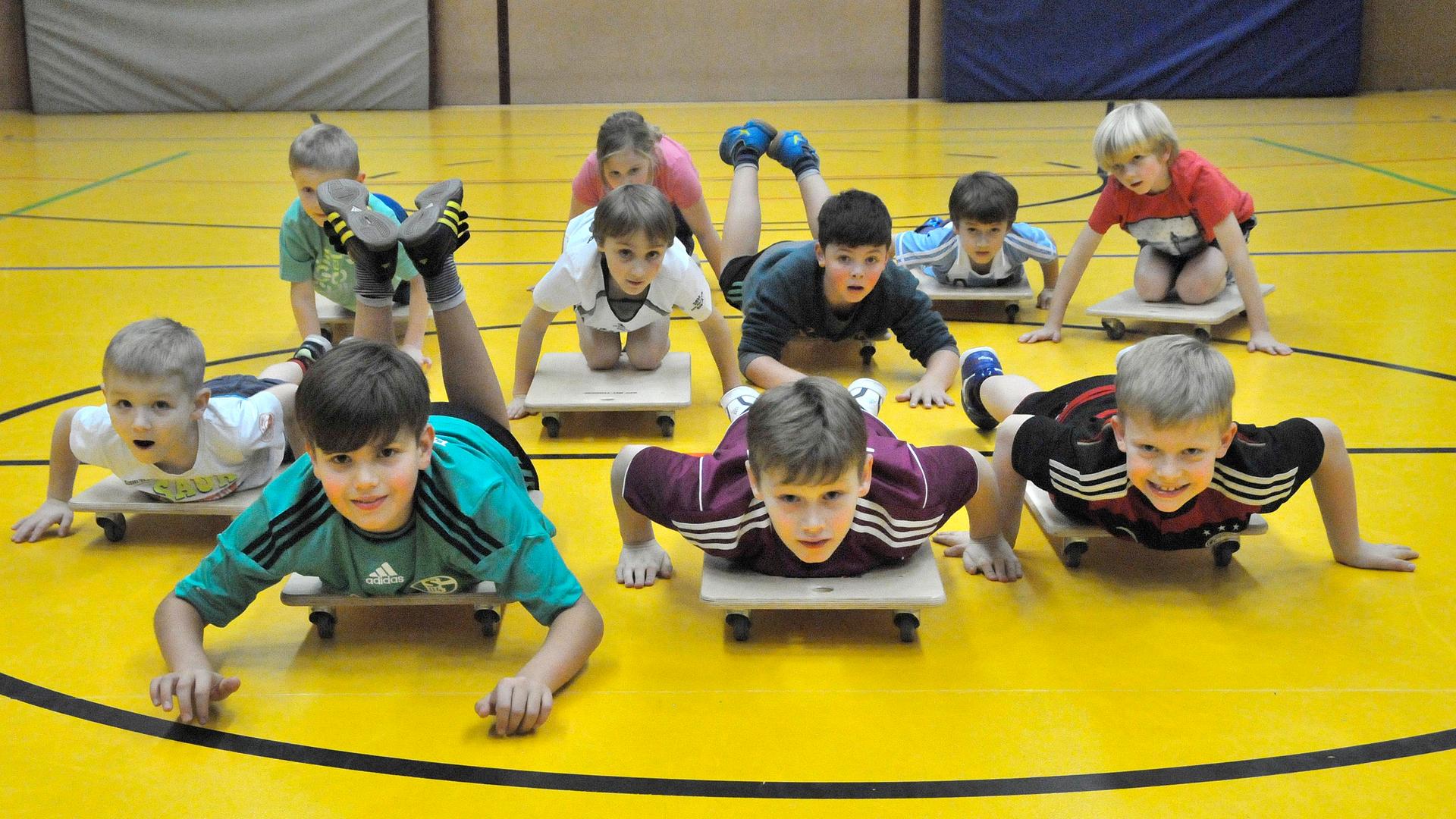 Kinder liegen auf Rollbrettern in einer Turnhalle. Kinder liegen auf Rollbrettern in einer Turnhalle.