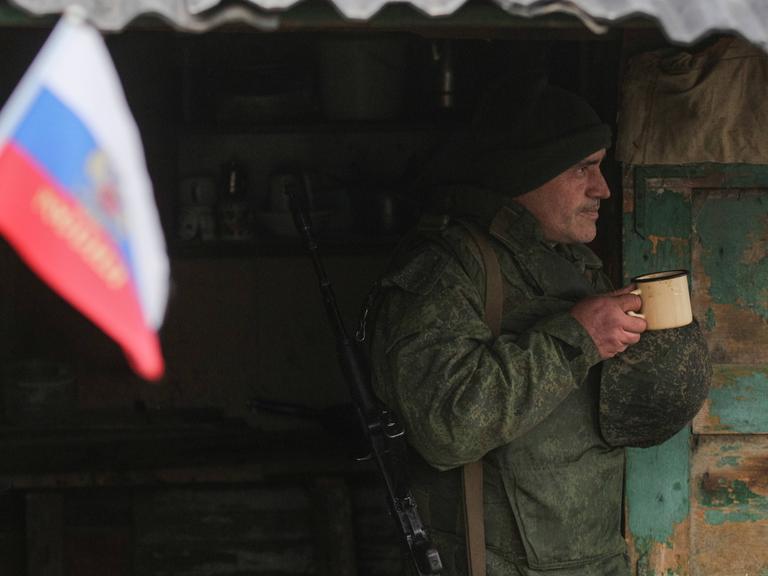 Separatisten der Volksrepublik Luhansk am 9. Dezember 2021.  Ein Offizier der separatistischen Volksrepublik Luhansk steht mit geschultertem Gewehr und einem Teepott in der Hand in einem Unterstand in der Nähe von Slawjanoserbsk in der Ostukraine an der Kontaktlinie zwischen den ukrainischen Regierungstruppen und den separatistischen Kräften der Volksrepublik Luhansk.
