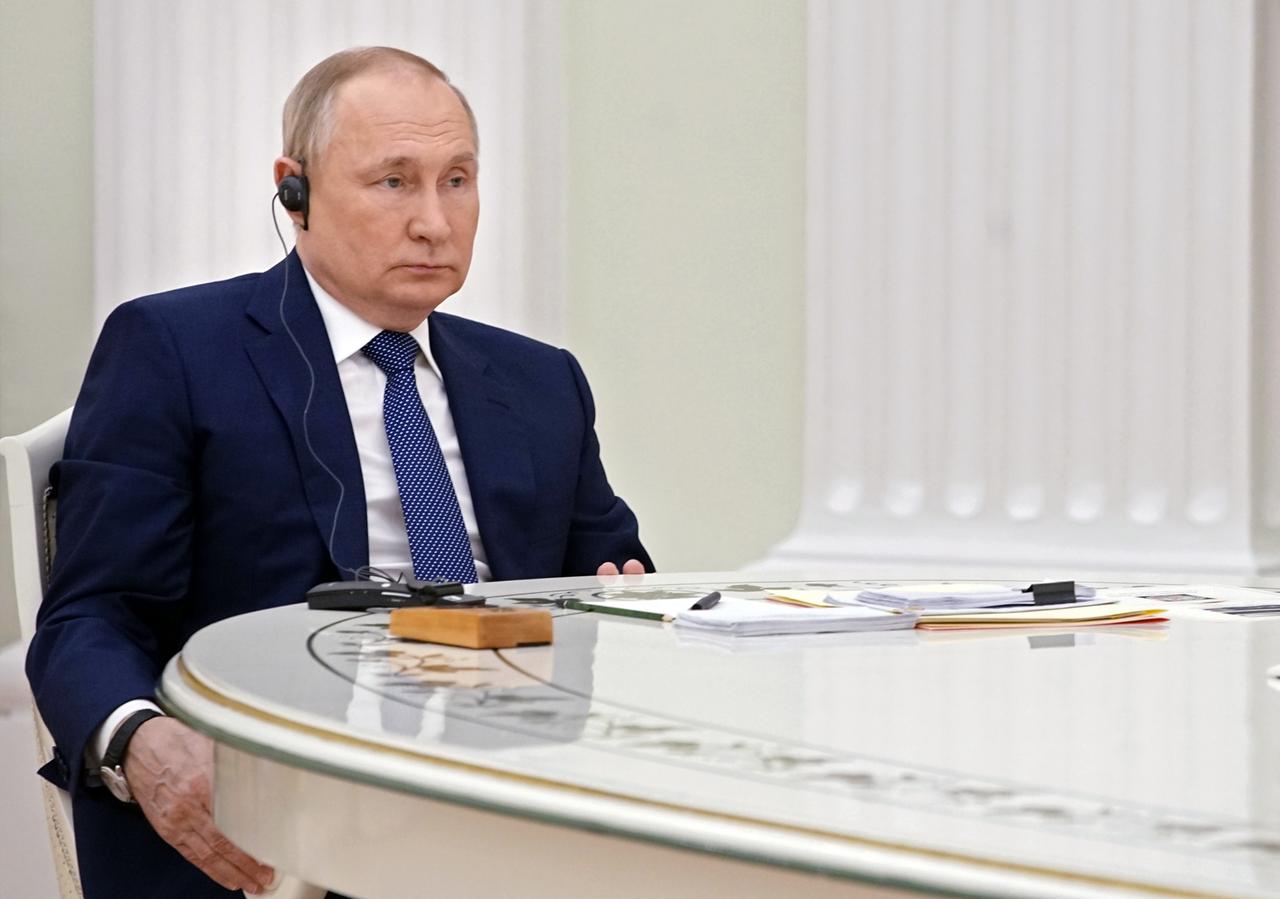Wladimir Putin sitzt an einem Tisch und hört zu.