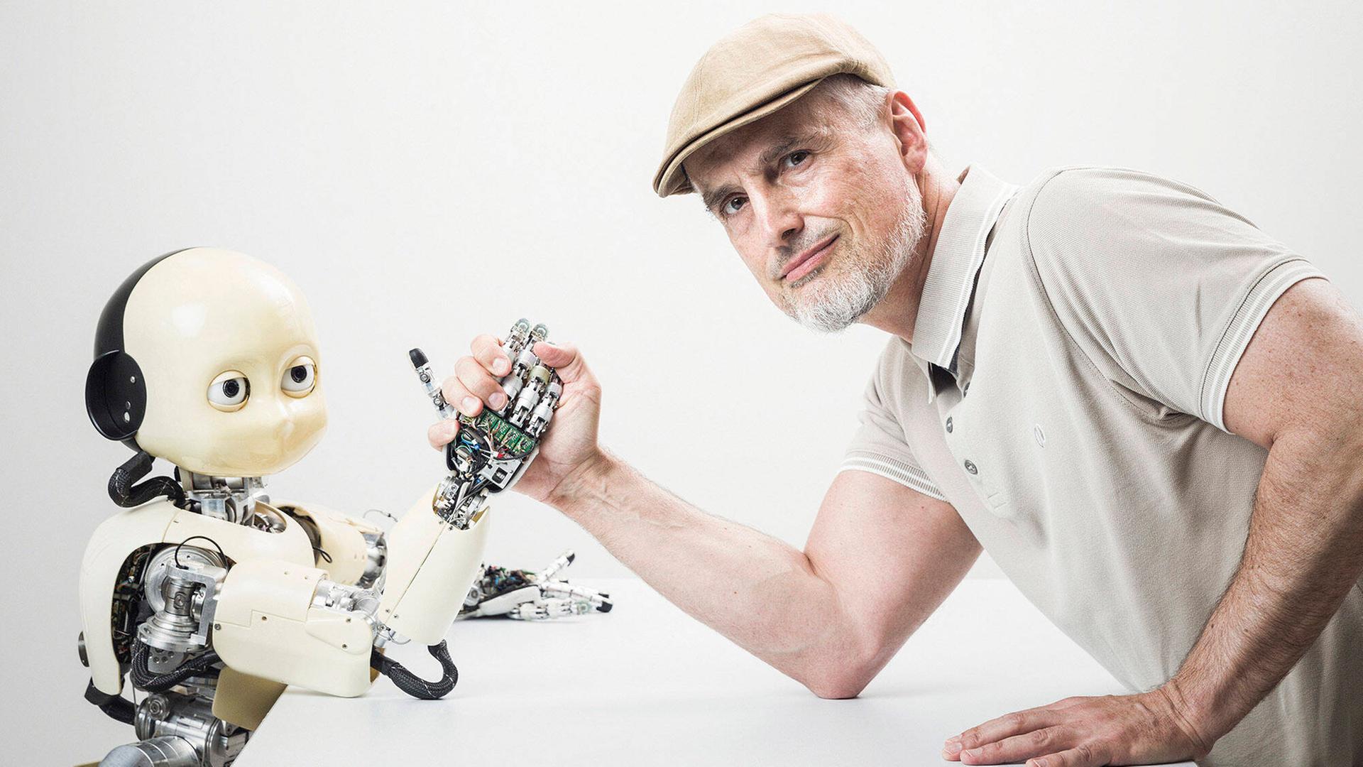 Ein Mann mittleren Alters (Informatiker und IDSIA Direktor Jürgen Schmidbauer) posiert beim Armdrücken mit dem humanoiden iCub-Roboter im Institut für künstliche Intelligenz IDSIA in Manno bei Lugano. Ein Mann mittleren Alters (Informatiker und IDSIA Direktor Jürgen Schmidbauer) posiert beim Armdrücken mit dem humanoiden iCub-Roboter im Institut für künstliche Intelligenz IDSIA in Manno bei Lugano.