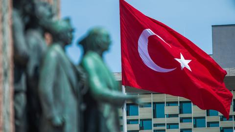 Das Denkmal mit der Darstellung von Mustafa Kemal Atatürk ist verschwommen vor der gehissten Flagge der Türkei zu sehen.