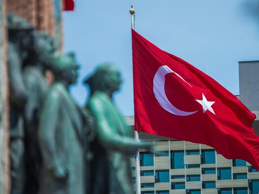 Das Denkmal mit der Darstellung von Mustafa Kemal Atatürk ist verschwommen vor der gehissten Flagge der Türkei zu sehen.