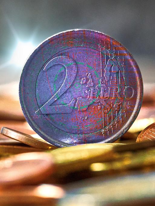 Fotomontage: zwei Euromünzen im Fokus, dahinter digitales Rauschen. Symbolbild für die anstehende Einführung des digitalen Euro.
